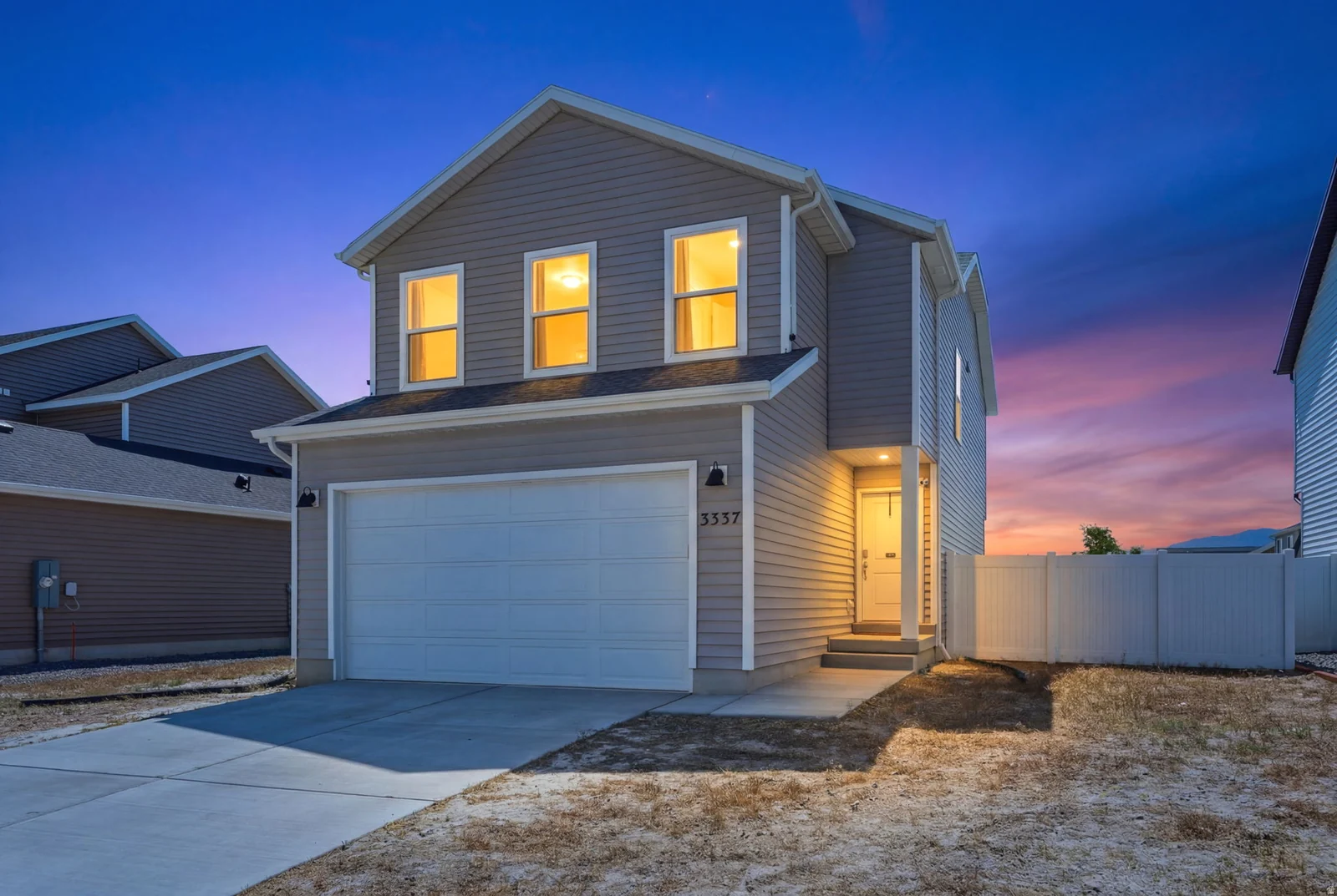 Contemporary two-story residence featuring light gray siding and a prominent two-car garage
